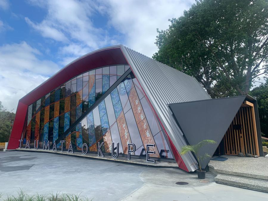Taumata o Kupe at dusk, red sculpted frame over a glazed façade